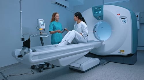 Woman Talking with Doctor Near CT Scanner in Hospital