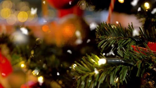 Green artificial christmas tree decorated at home with snowfall for new year holidays