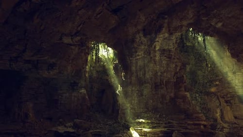 Peaceful Cavern Illuminated By Golden Beams and Mosscovered Walls