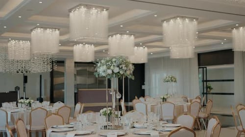 Elegant wedding hall with chandeliers and tables adorned with floral centerpieces