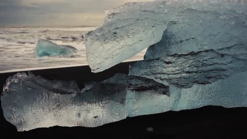 Slow motion shots of blue icebergs on Diamond beach in Iceland. Black sand beach at sunset. Differen