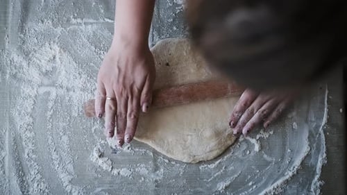 Woman Rolling Dough with Rolling Pin in Kitchen