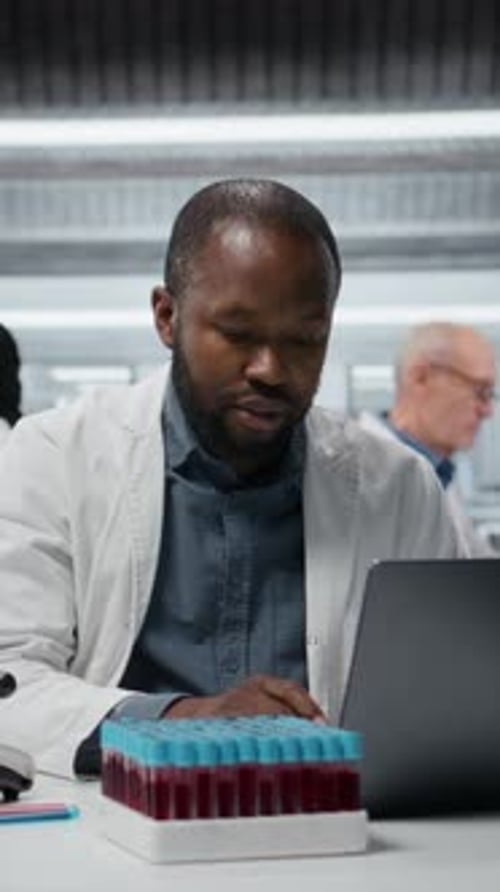Scientist Analyzing Blood Samples in Lab with Laptop