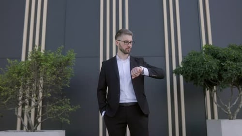 Confident Businessman in a Stylish Suit Checking His Watch in a Modern Urban Setting