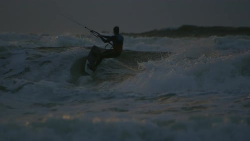 In rays of setting sun, kitesurfer enjoys freedom and excitement of kiteboarding, feeling rush of ad