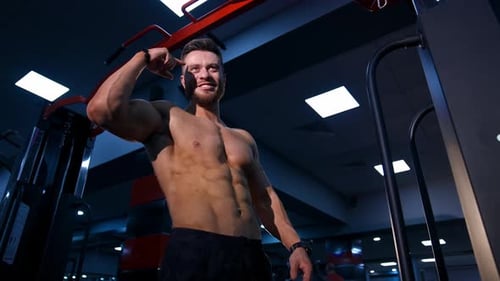 Healthy bodybuilder indoors. Smiling young man with sportive body talking in the modern gym