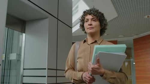 Executive Manager Carrying Paperwork and Walking in Office Hallway