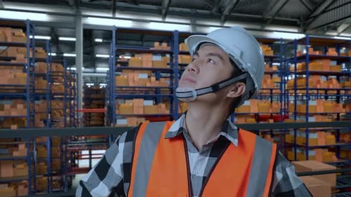 Asian Male Engineer Standing With Arms Akimbo Looking Around The Warehouse