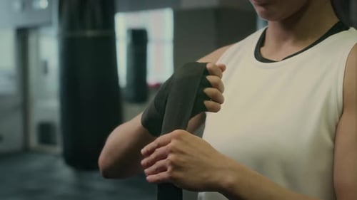 Woman Wrapping Hands in Boxing Wraps at Gym