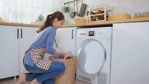 Woman Loading Clothes into Washing Machine in Kitchen