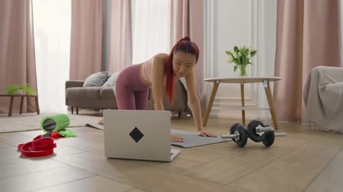 Pretty Asian Woman Viewing Fitness Tutorial Video at Laptop Display and Training Home Sport Workout