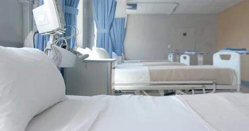 Row of empty, freshly made beds and equipment in empty hospital ward, copy space, slow motion