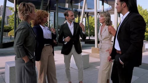 Professional business team collaborating outside modern office building, discussing project strategy