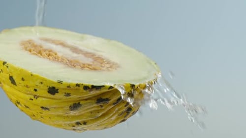 La moitié d'un melon jaune avec des os, on verse de l'eau dessus, sur fond de ciel bleu, gros plan, Slow mo