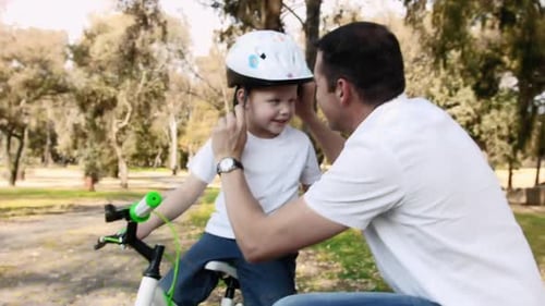 Father teaches son about bicycle safety on park pathway adventure