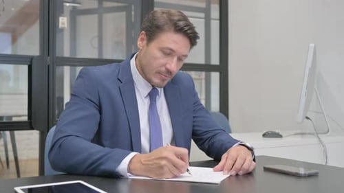 Mature Adult Businessman Writing Documents at Work