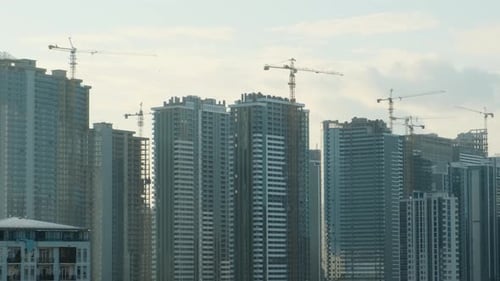 Krane arbeiten auf der Baustelle eines modernen Stadtviertels mit mehrstöckigen Wolkenkratzern