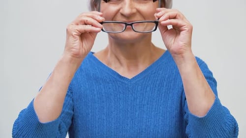Smiling Senior Woman Puts on Reading Glasses