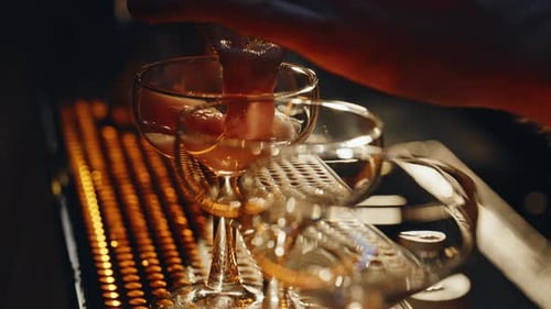 Hands Pouring Alcohol Cocktail in Glasses Standing at Bar Counter Closeup