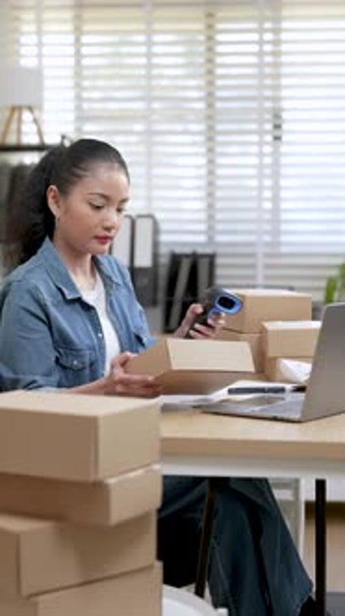 Woman Scanning Packages for Delivery in Office
