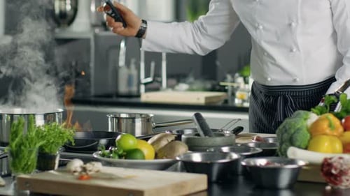 Professioneller Koch erhitzt Öl in einer Pfanne. Kochen im Flambe-Stil. Er arbeitet in einer modernen Küche mit Lo