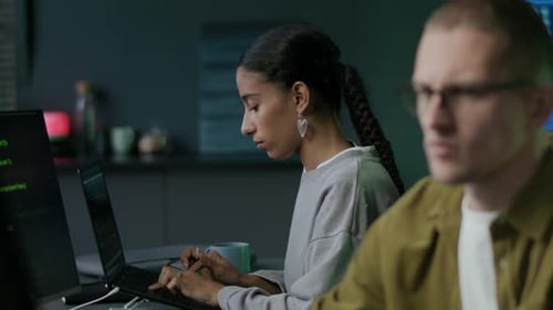 Junge, konzentrierte, vielfältige Programmierer, die nachts im Büro am PC arbeiten