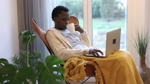 mulher afro-americana milenar com cabelo curto usando laptop em casa, sentada na mesa. Trabalho remoto