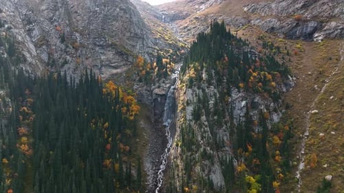 Drone view of a majestic waterfall surrounded by autumn colors