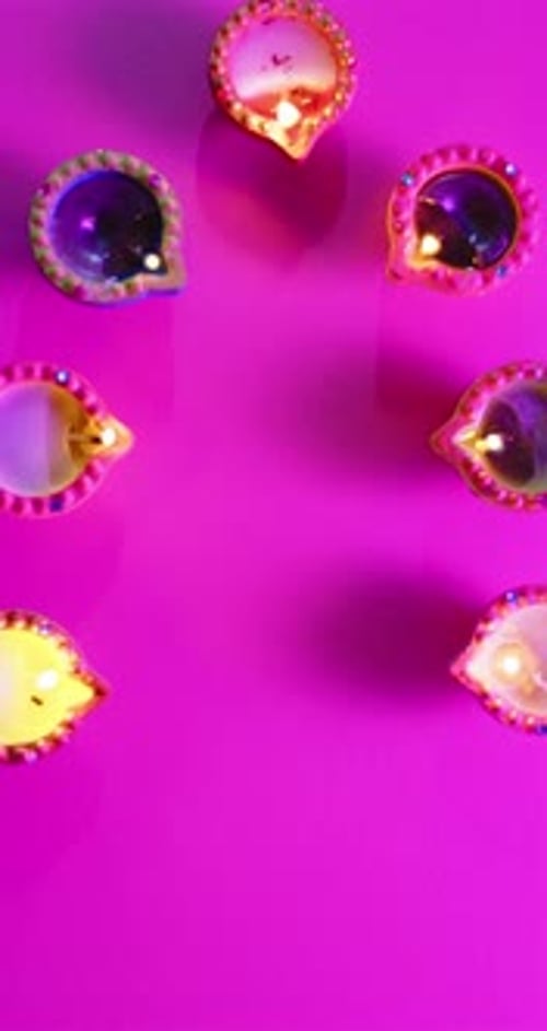 Vidéo verticale de bougies allumées en rang célébrant Diwali sur fond rose, avec espace de copie