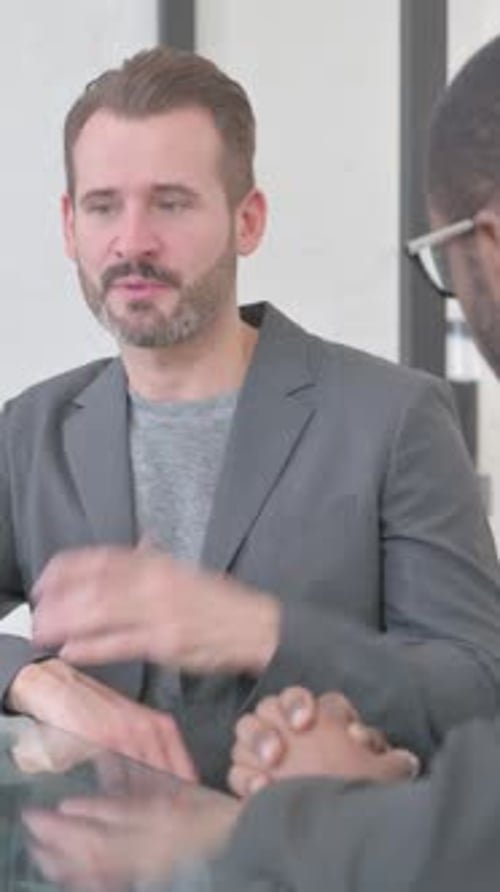 Two Men in Business Attire Talking in Office