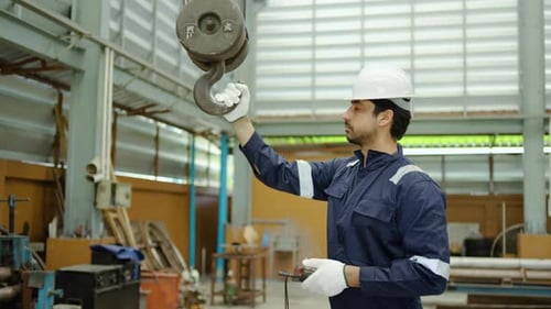 ingénieur de sexe masculin exploitant un pont roulant industriel avec une télécommande dans un entrepôt