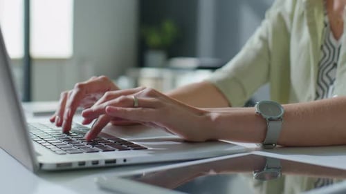 Hände einer Geschäftsfrau, die am Laptop am Schreibtisch arbeitet
