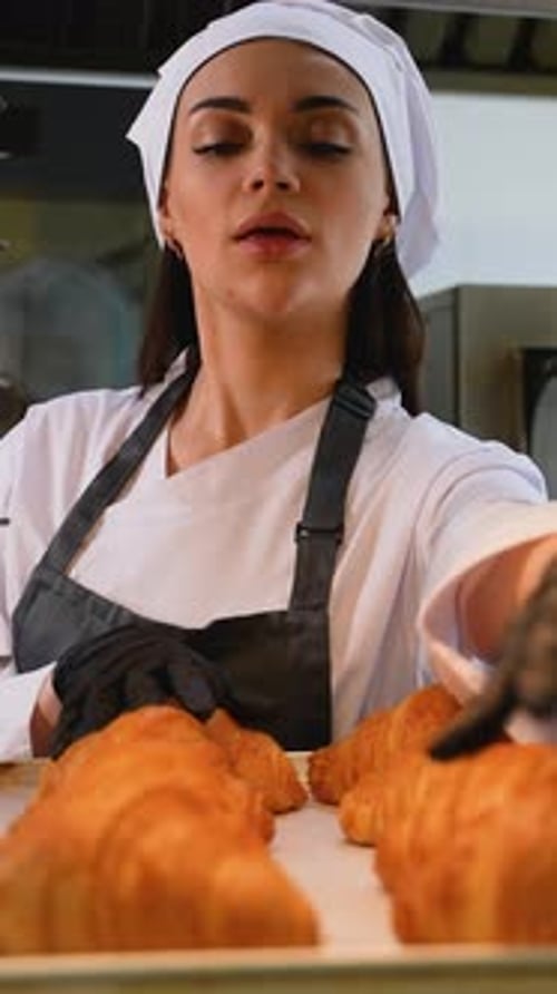 Woman Baker Arranging Golden Croissants on Tray