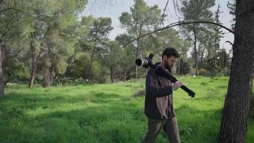 Content creator walking through forest carrying camera gear
