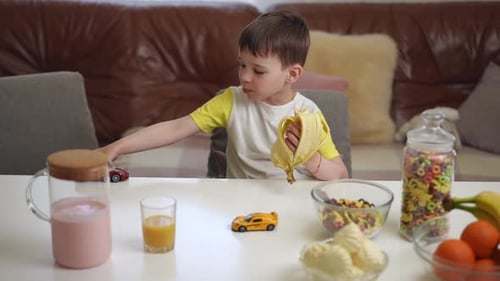 Young Boy Eating Banana While Playing with Cars