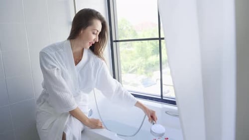 Woman Preparing Relaxing Bath with Rose Petals