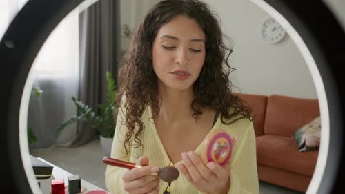 Tutorial de maquillaje para una mujer joven filmando con una luz anular en casa