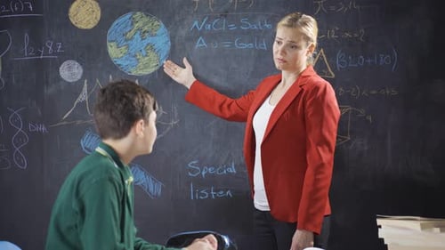 Teacher Explains Lesson to Student at Chalkboard