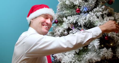 Man Decorating Christmas Tree Wearing Santa Hat