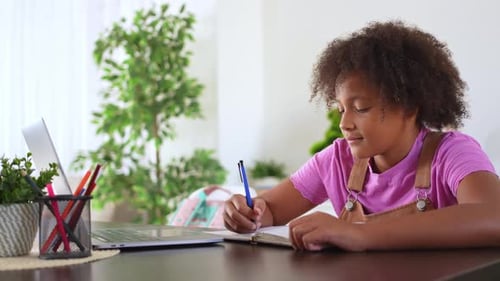 Girl Studies with Laptop and Notebook at Desk