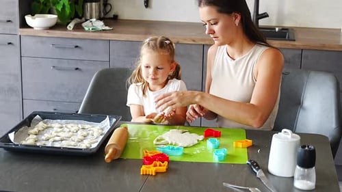 Young Adult and Child Baking Together in Kitchen