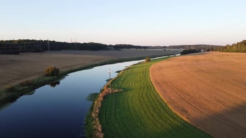 Small river surrounded by fields during the sunset. Countryside. Drone shot
