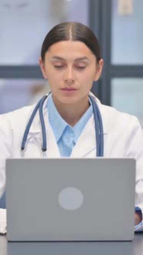 Doctor Works at Laptop in Hospital Clinic Setting