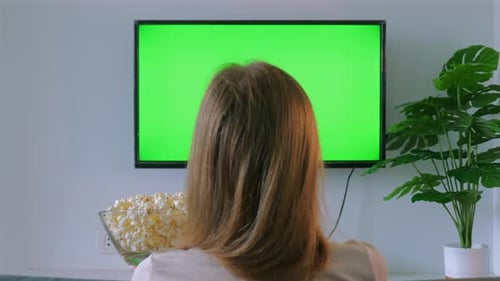 Woman with Popcorn Watching TV with Green Screen at Home Perfect for