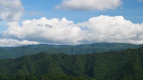 Mountain's Clear Day: Dynamic White Clouds Against a Blue Sky.
