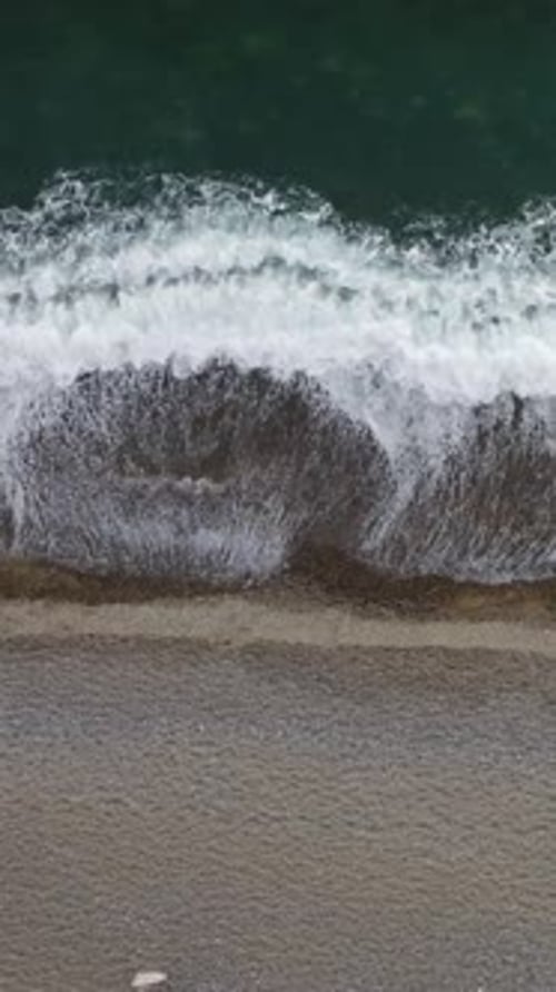 Aerial Vertical View of Beach with Wave Caressing Shore Sun Glare Small Waves on the Water Surface