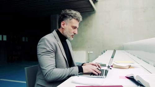 Reifes Lehramtsstudium mit Laptop in einer geräumigen Bibliothek der Universität