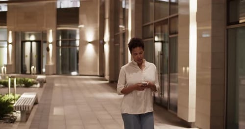Woman Walks Using Cellphone at Night in City