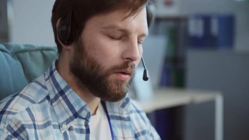 A Focused Man with a Beard Works in a Virtual Meeting Dedicated