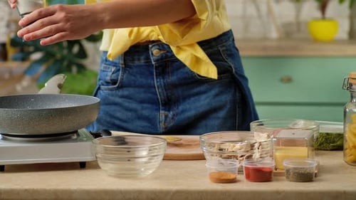 Woman Cooking Adding Spices to Food in Kitchen
